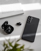 a pair of black earbuds sitting next to an open book