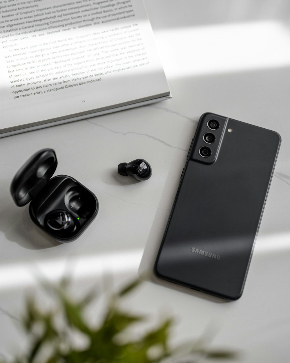 a pair of black earbuds sitting next to an open book