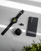 a smart watch and ear buds on a table