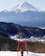 A happy traveler holding a compact travel kit with Mount Fuji in the background.