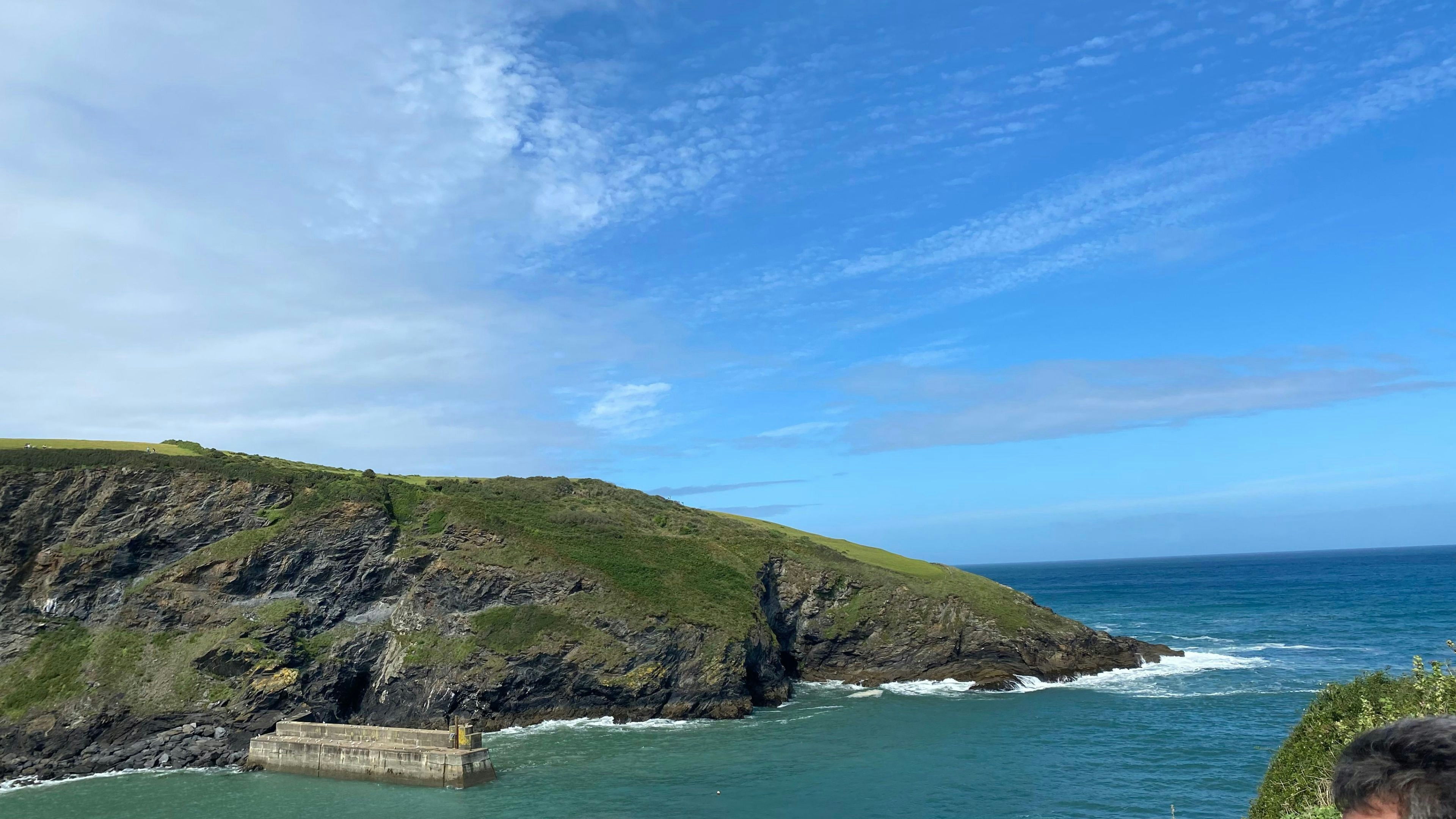 a man sitting on a bench looking at the ocean, 