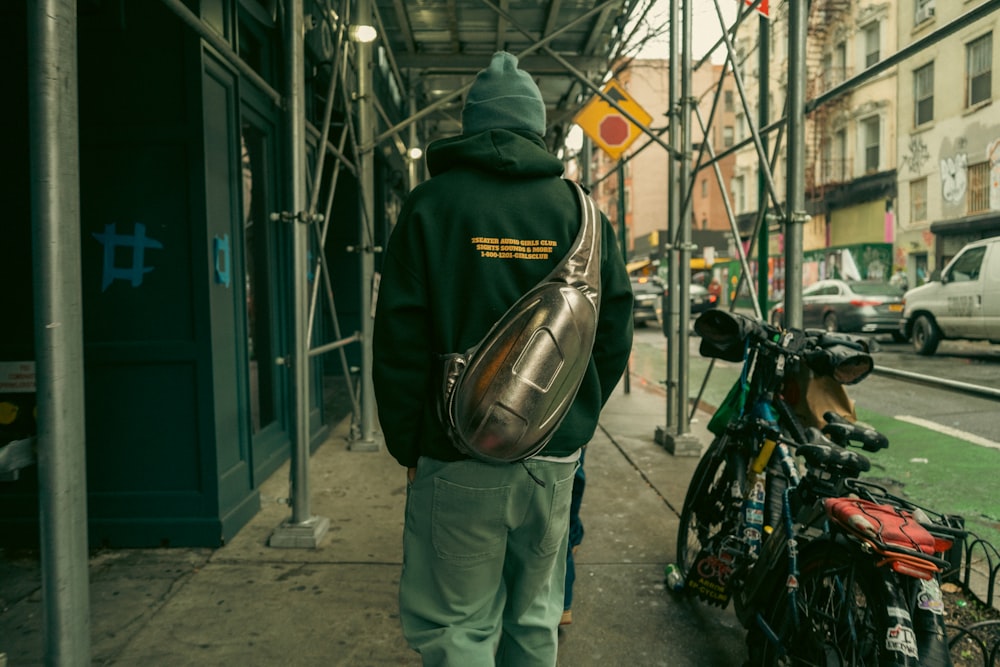 a man walking down a sidewalk next to a bunch of bikes