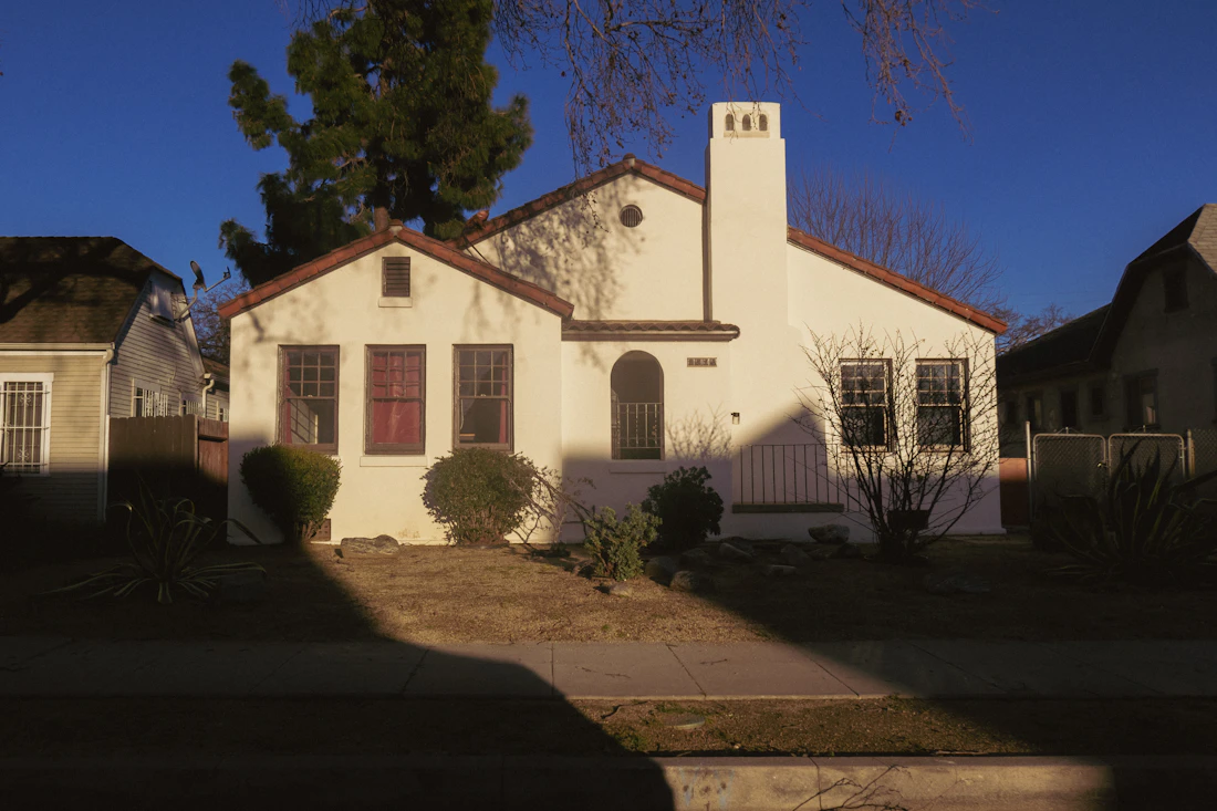 Modest white home with red shutters and a red front door