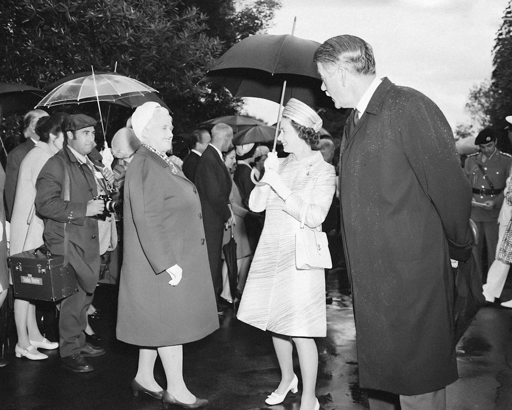 a black and white photo of two people holding umbrellas