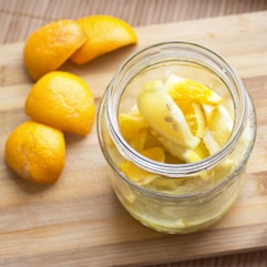 a jar filled with sliced oranges on top of a wooden cutting board