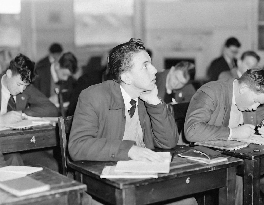 a group of men sitting at desks in a classroom