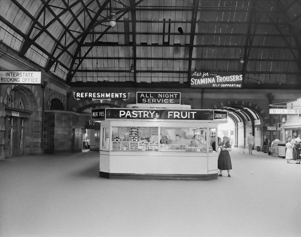 a black and white photo of a woman standing in a train station
