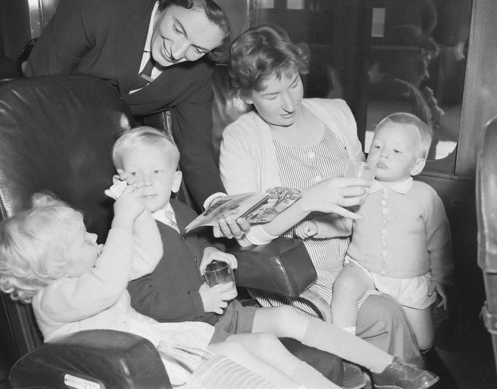 a black and white photo of a family reading a book