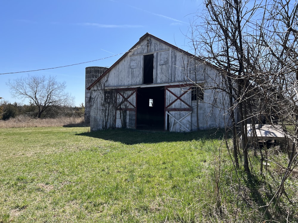 an old barn sits in a field of grass