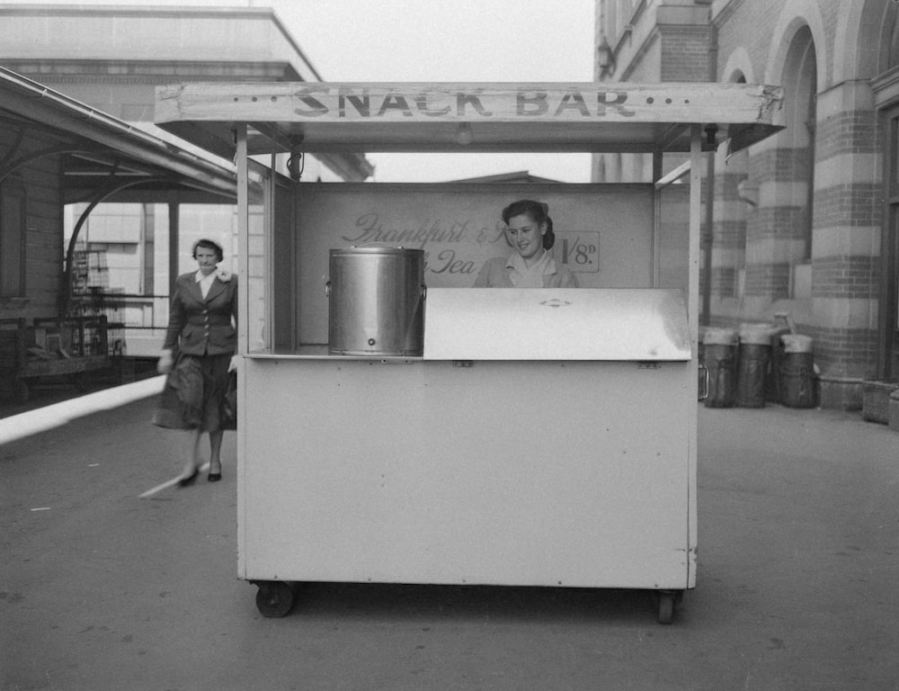 a woman standing next to a small ice cream cart