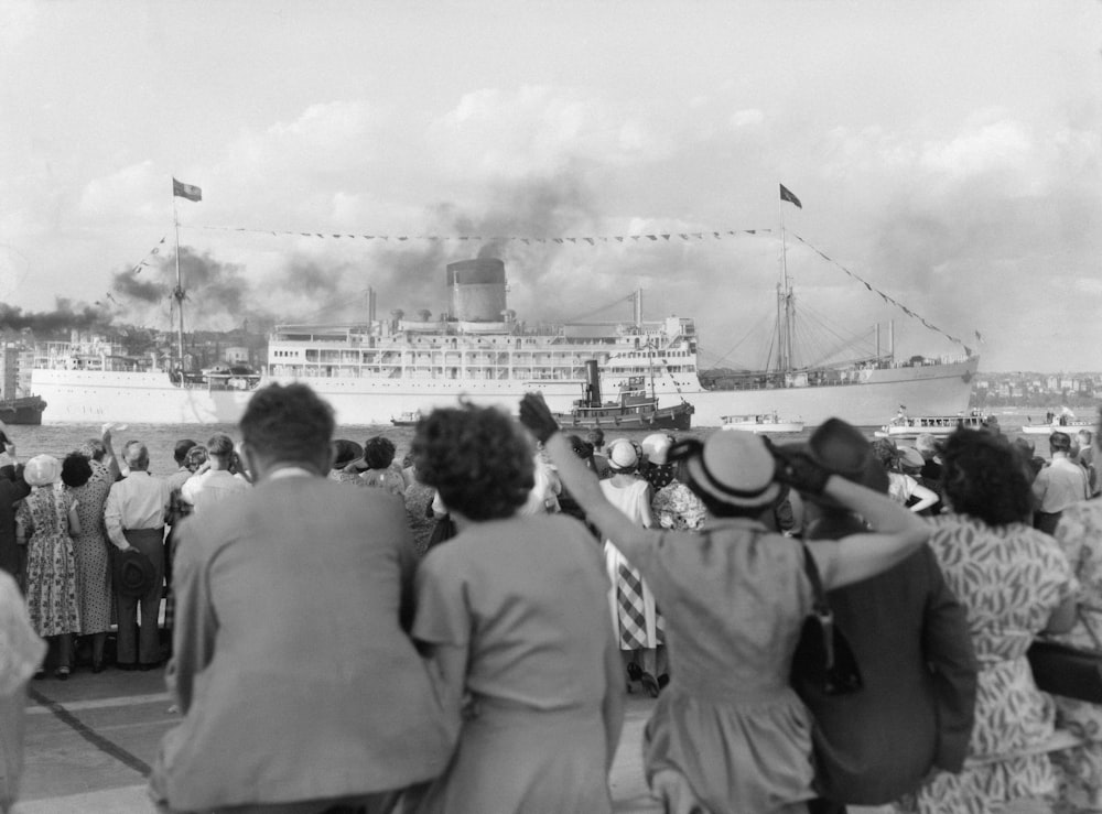 a group of people watching a large boat in the water