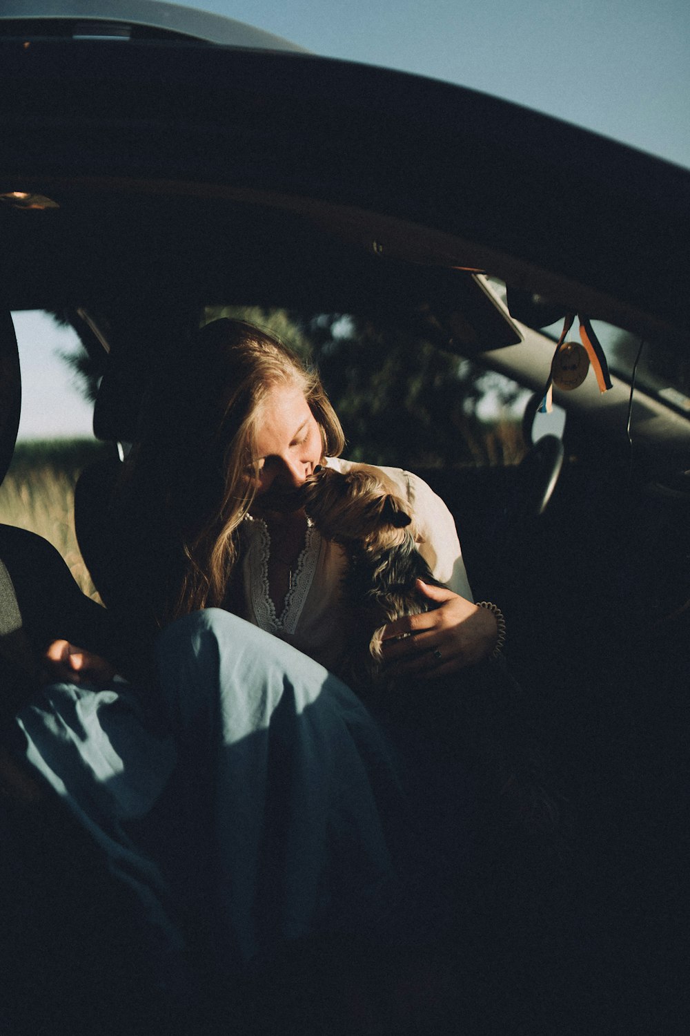 a woman sitting in the back seat of a car holding a cat