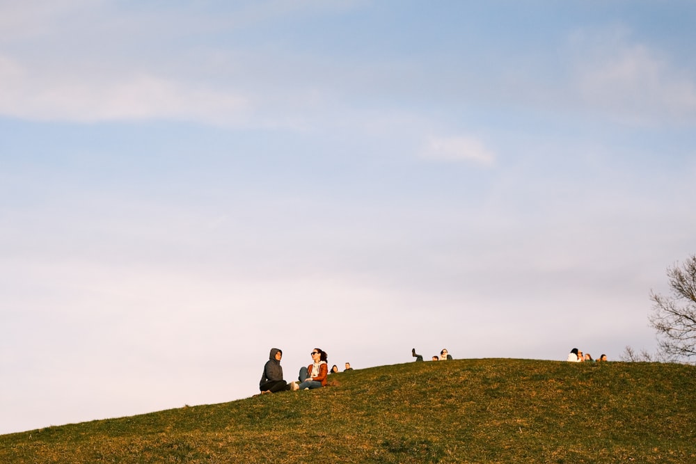 a group of people sitting on top of a lush green hillside