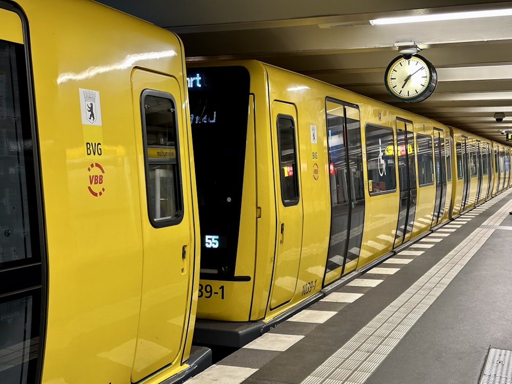 a yellow train parked at a train station next to a clock