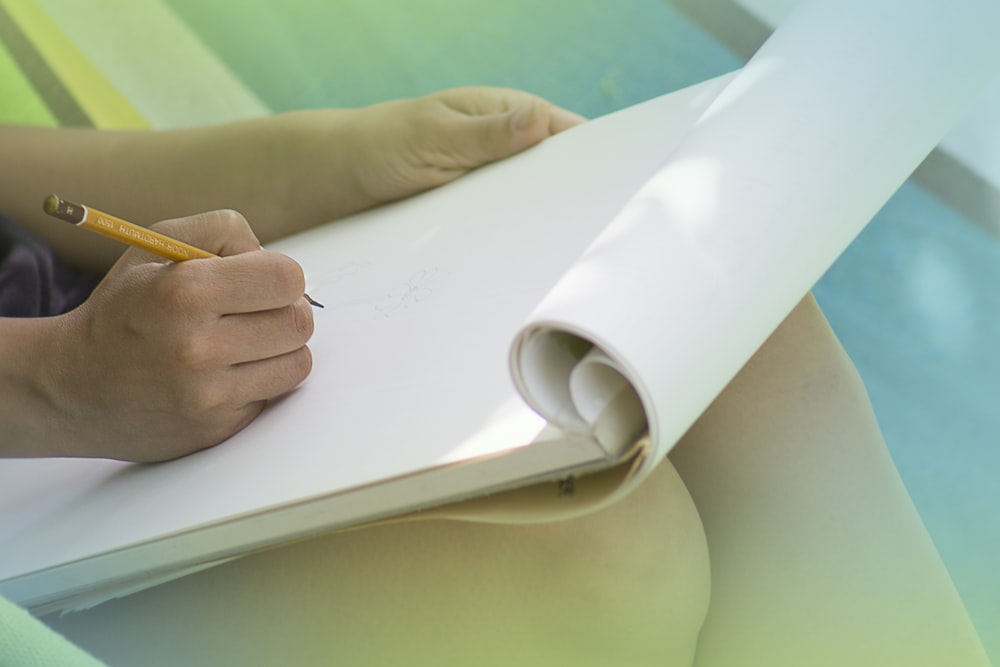 a person writing on a piece of paper with a pencil