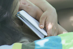 A close-up of hands holding a book on self-inquiry, softly lit with a calm, white backdrop.