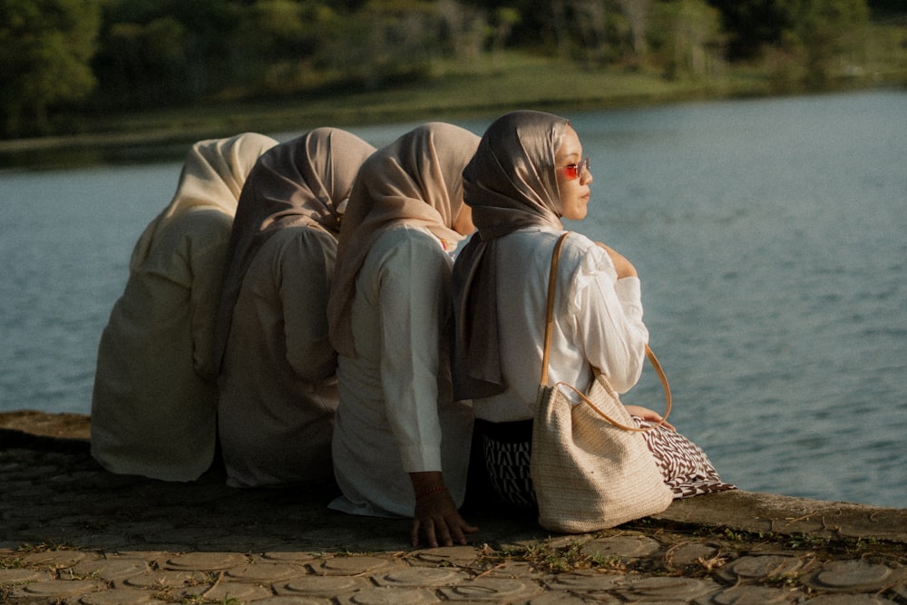 a group of women sitting next to a body of water