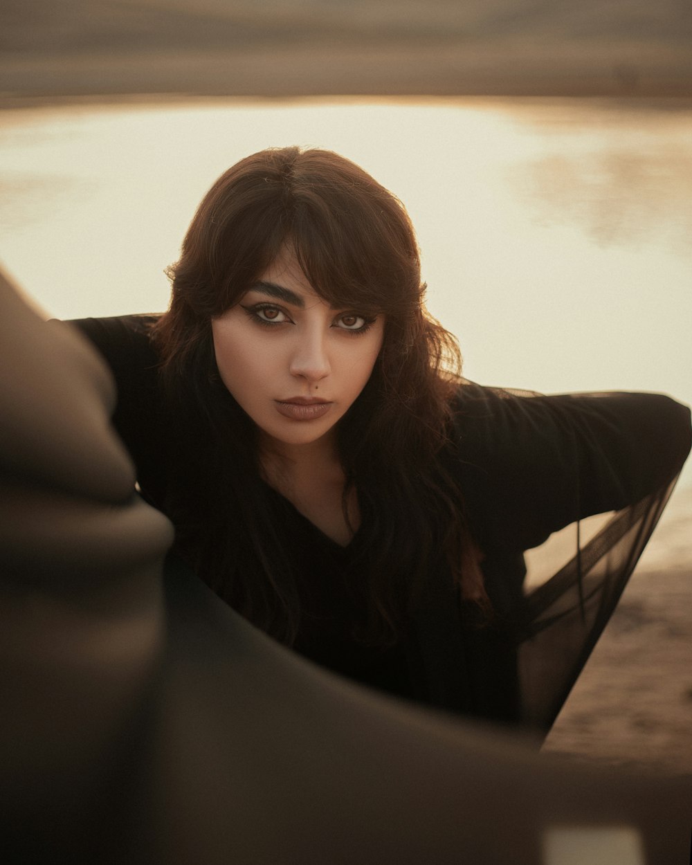 a woman is posing for a picture near a body of water