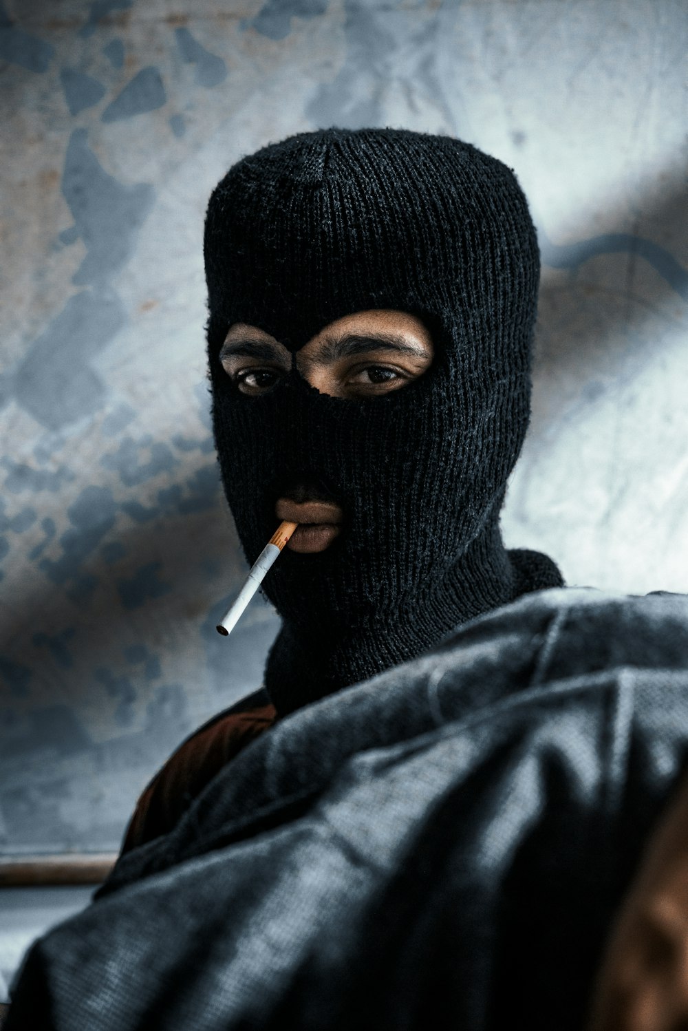 a man in a black mask smoking a cigarette
