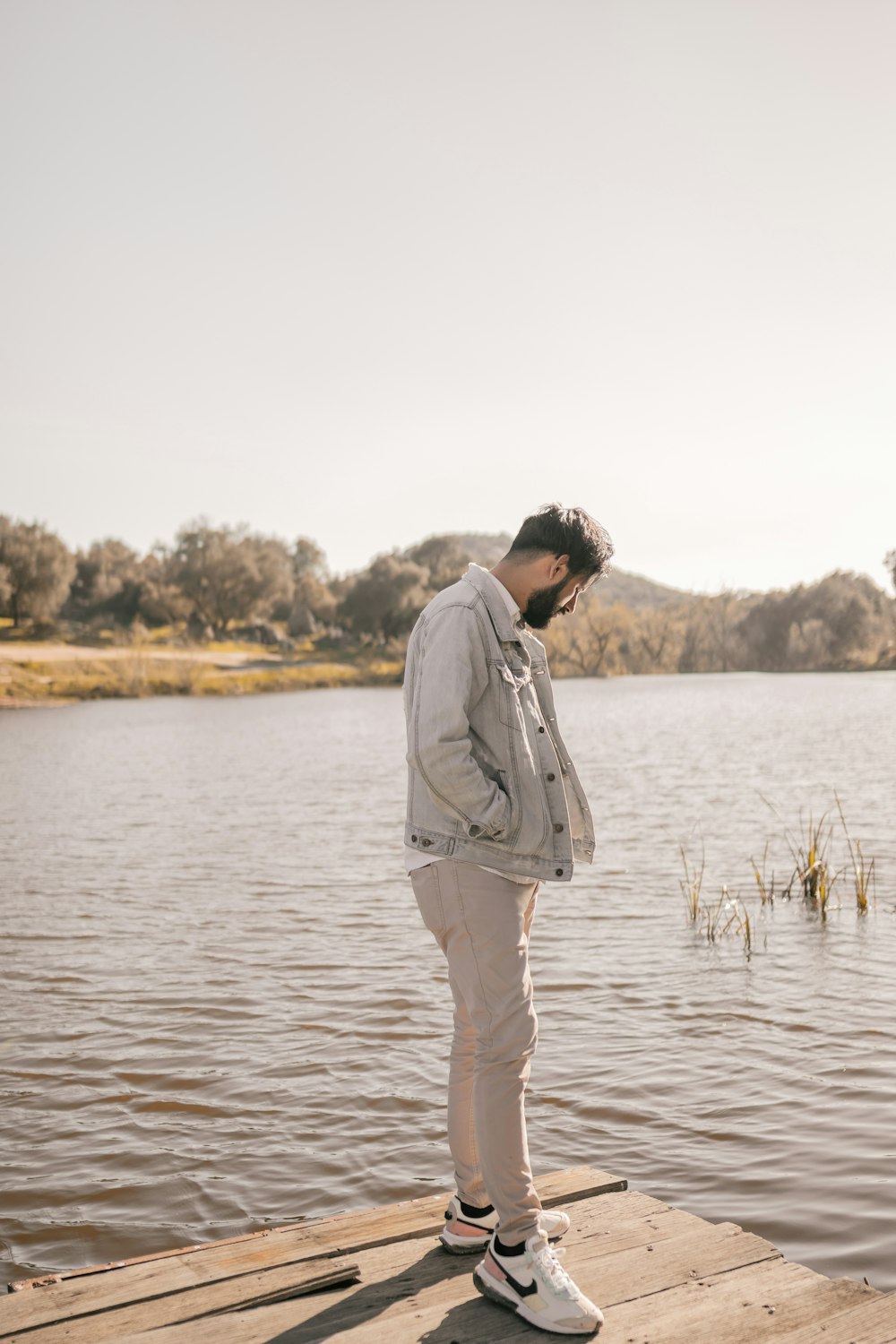 a man standing on a dock next to a body of water