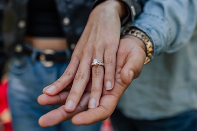 A sparkling diamond ring held gently between two fingers.