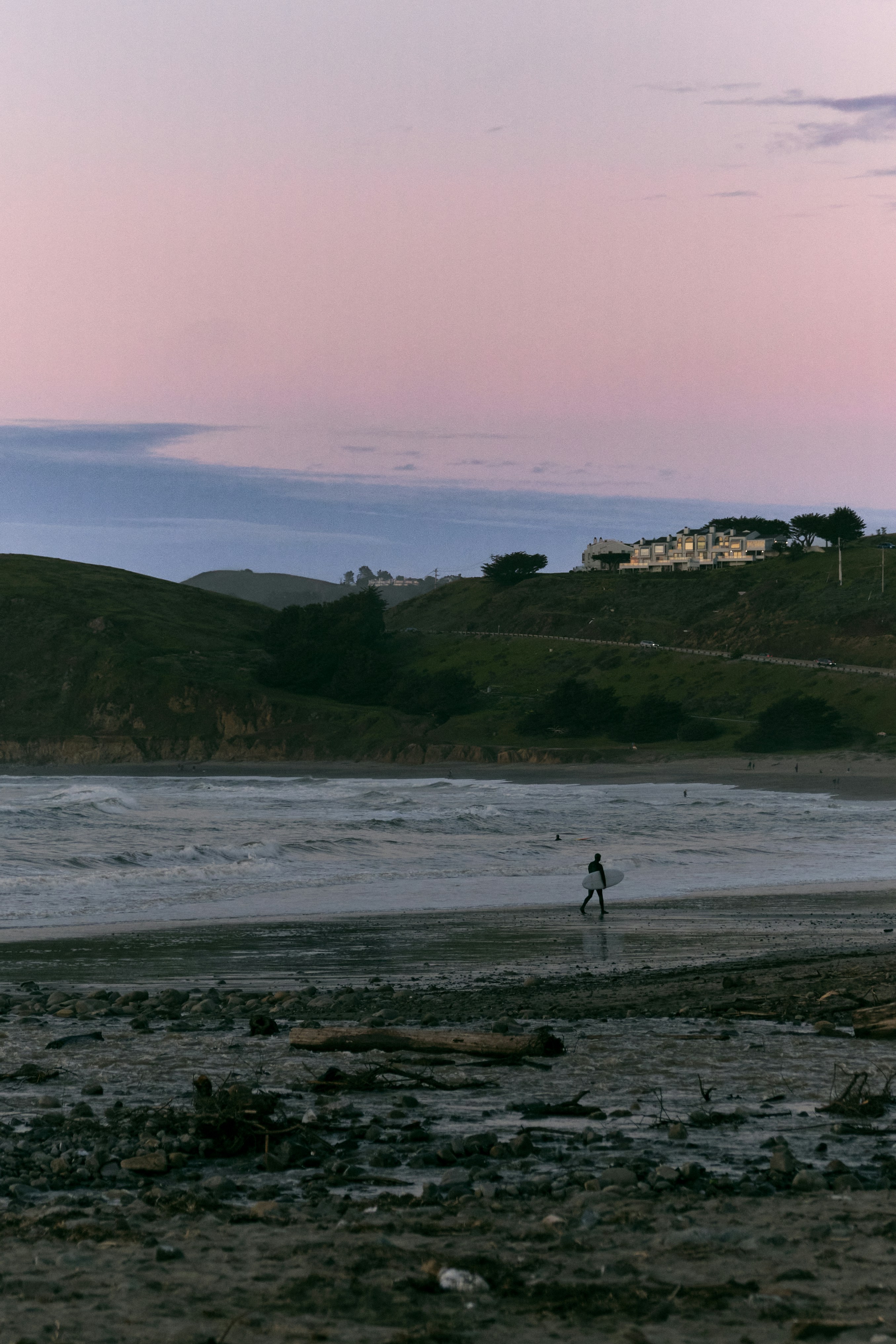a person is walking on the beach with a surfboard