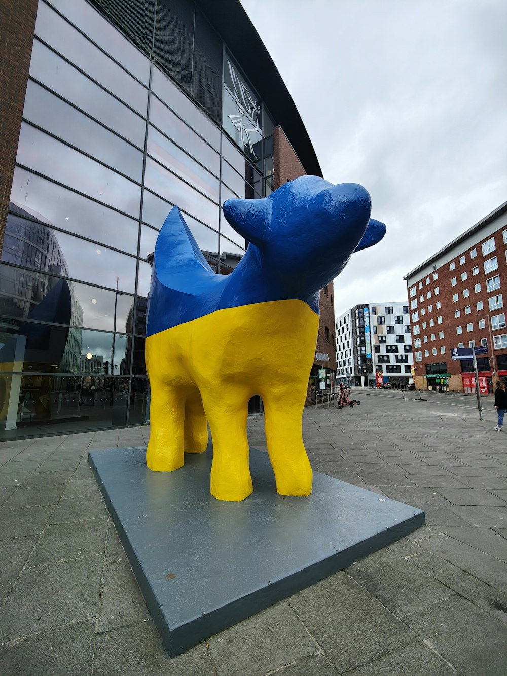a statue of a blue and yellow dog in front of a building