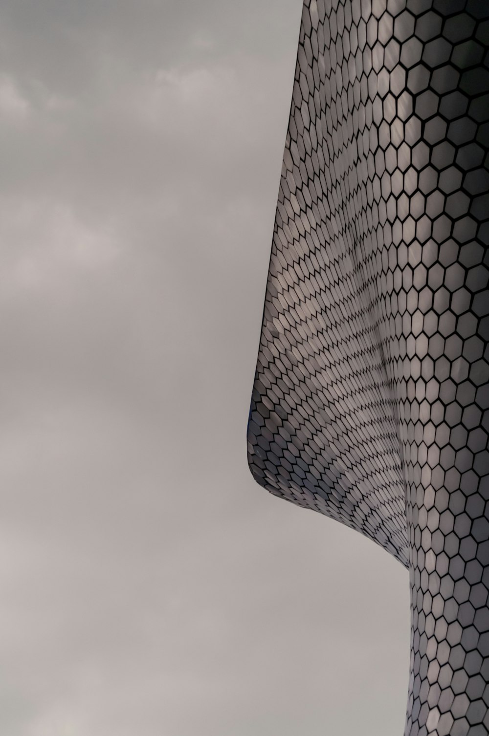 a tall building with a curved roof against a cloudy sky