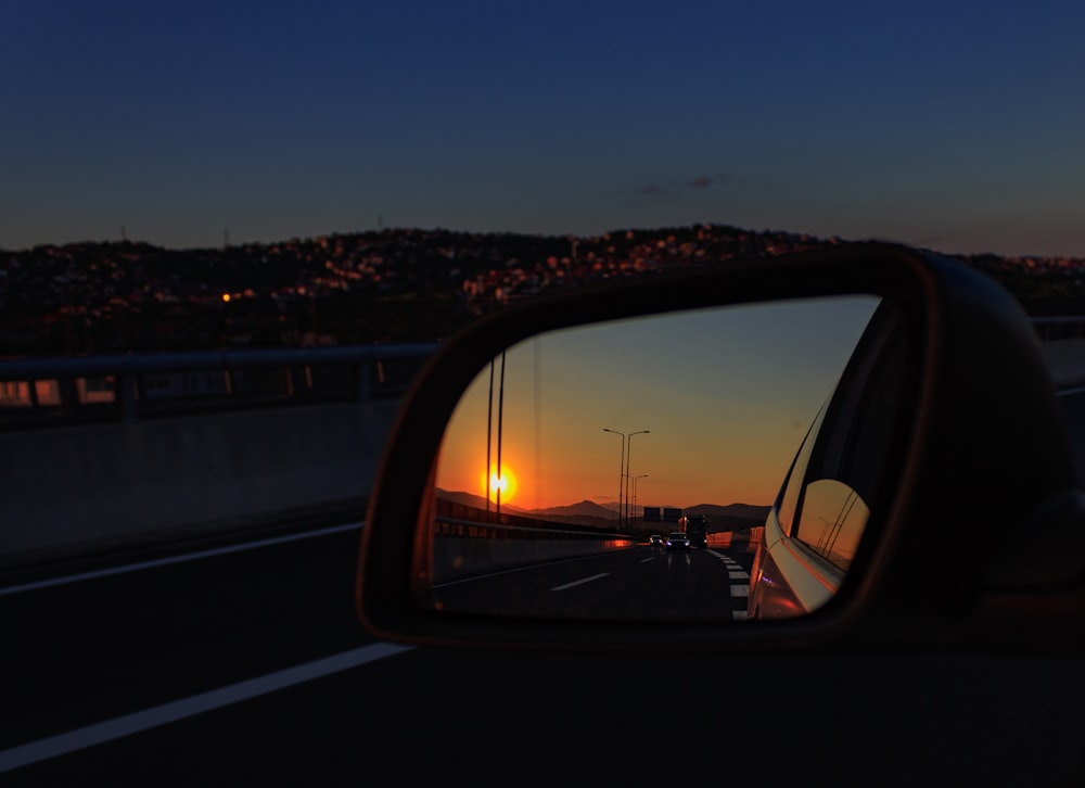 a car's side view mirror reflecting a sunset