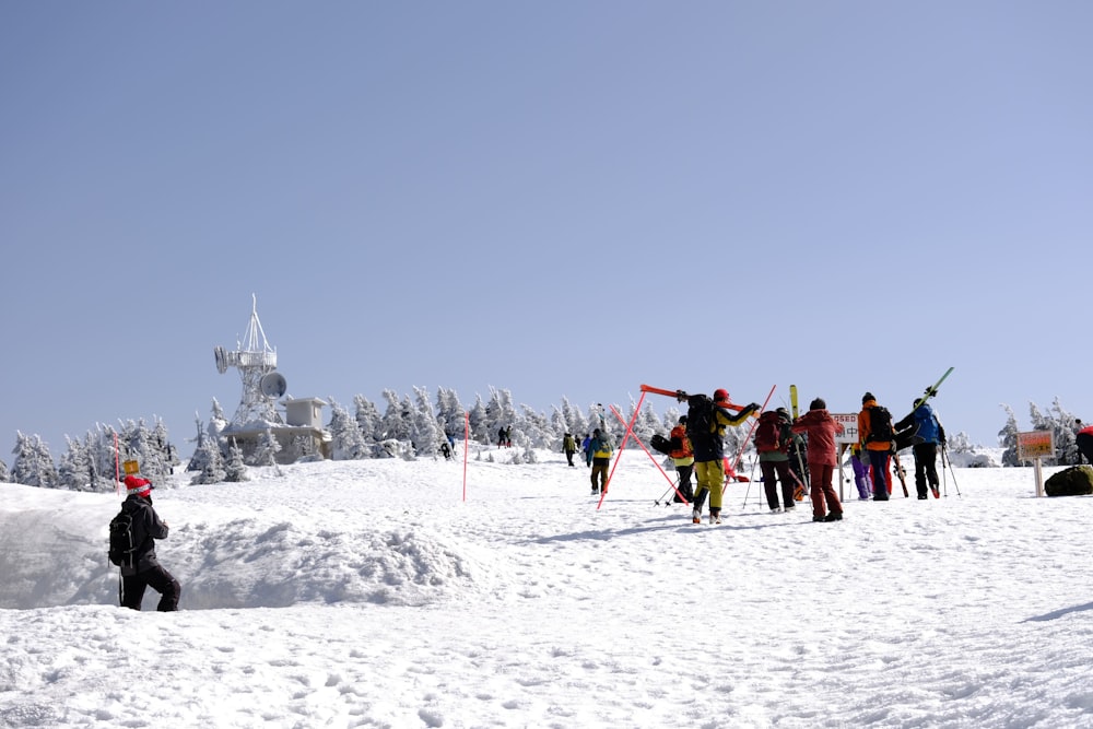 Un grupo de personas de pie en la cima de una ladera cubierta de nieve