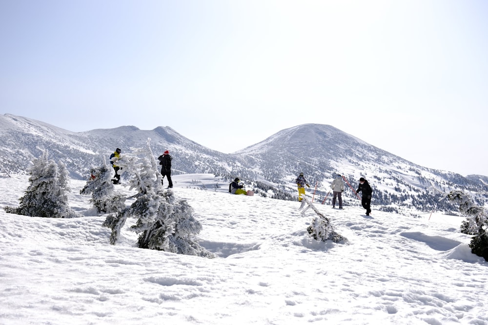 Un grupo de personas de pie en la cima de una ladera cubierta de nieve