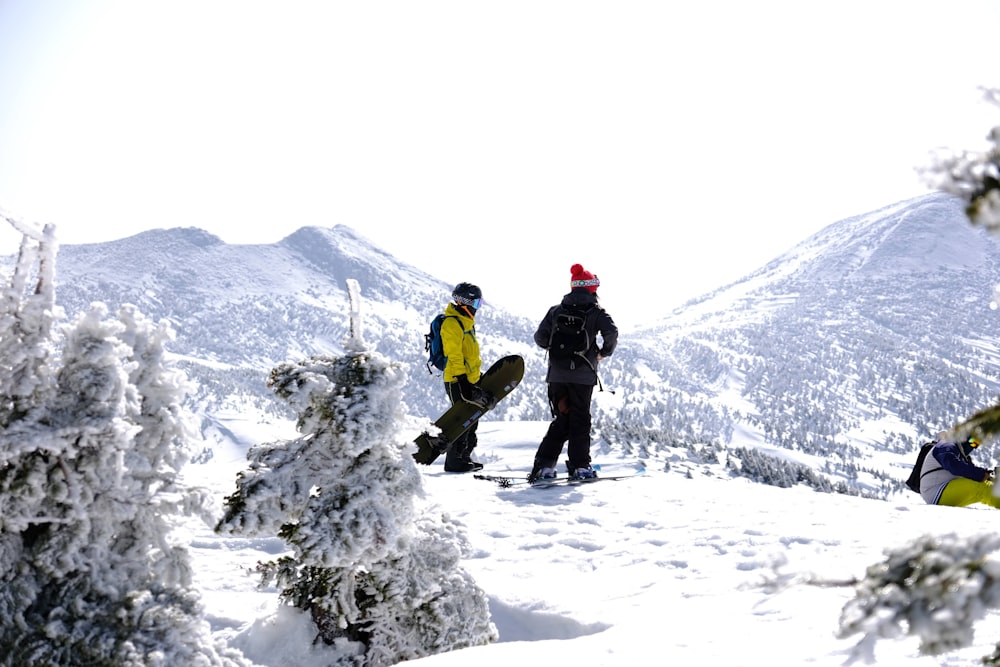 two snowboarders are standing on a snowy mountain