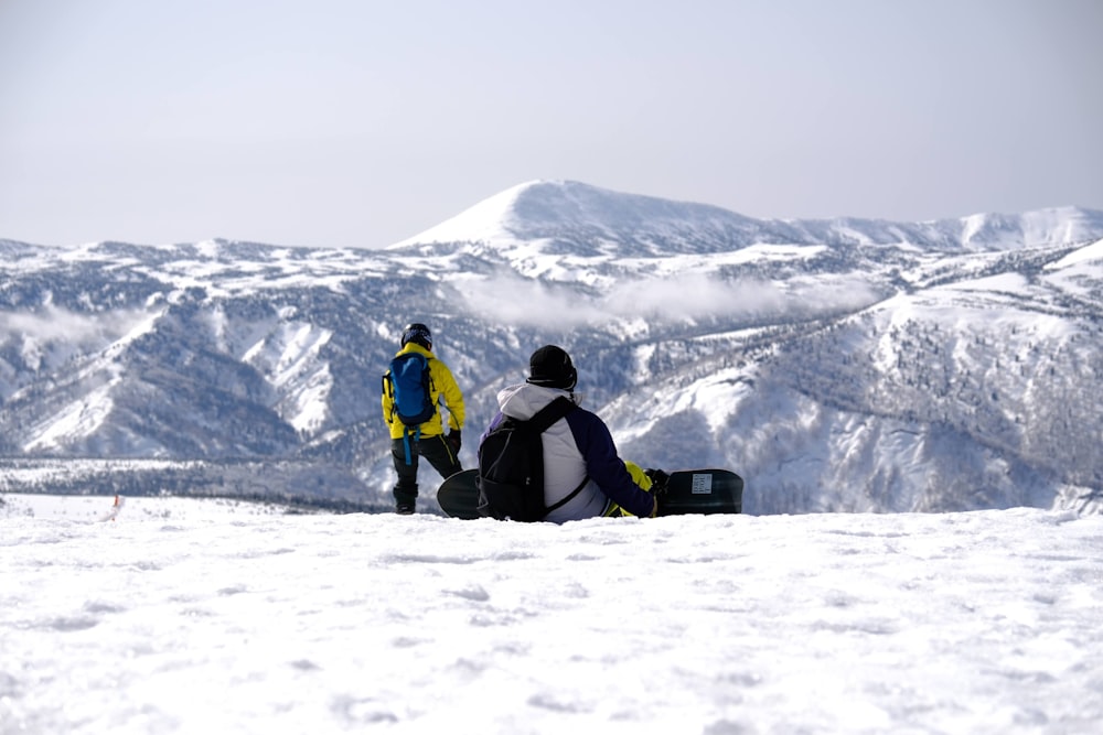 Un par de personas de pie en la cima de una pendiente cubierta de nieve