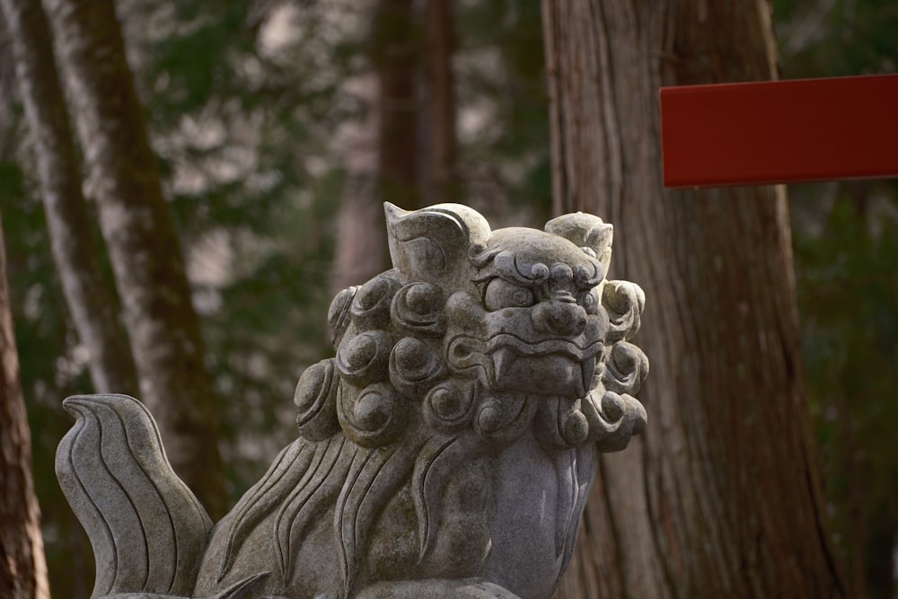 a statue of a lion in front of some trees
