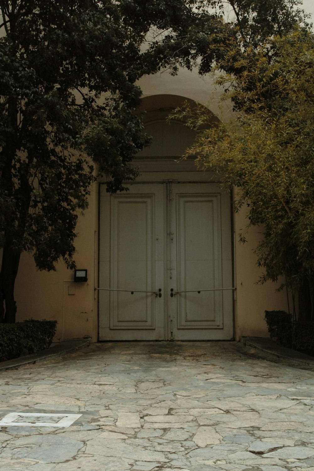 a large white door sitting between two trees