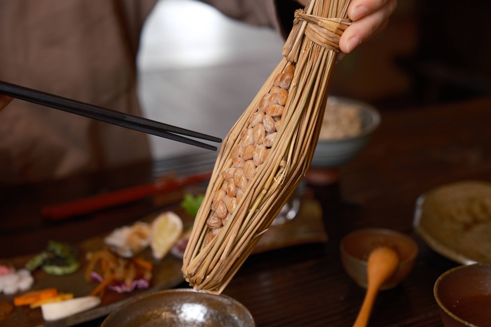 a person holding a stick over a bowl of food