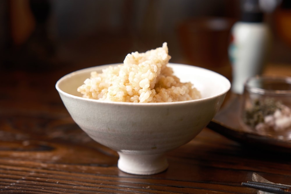 a white bowl filled with rice on top of a wooden table