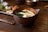 Close-up of a rustic ceramic bowl filled with rich, dark miso paste on a wooden table.