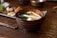 Close-up of a rustic ceramic bowl filled with rich, dark miso paste on a wooden table.