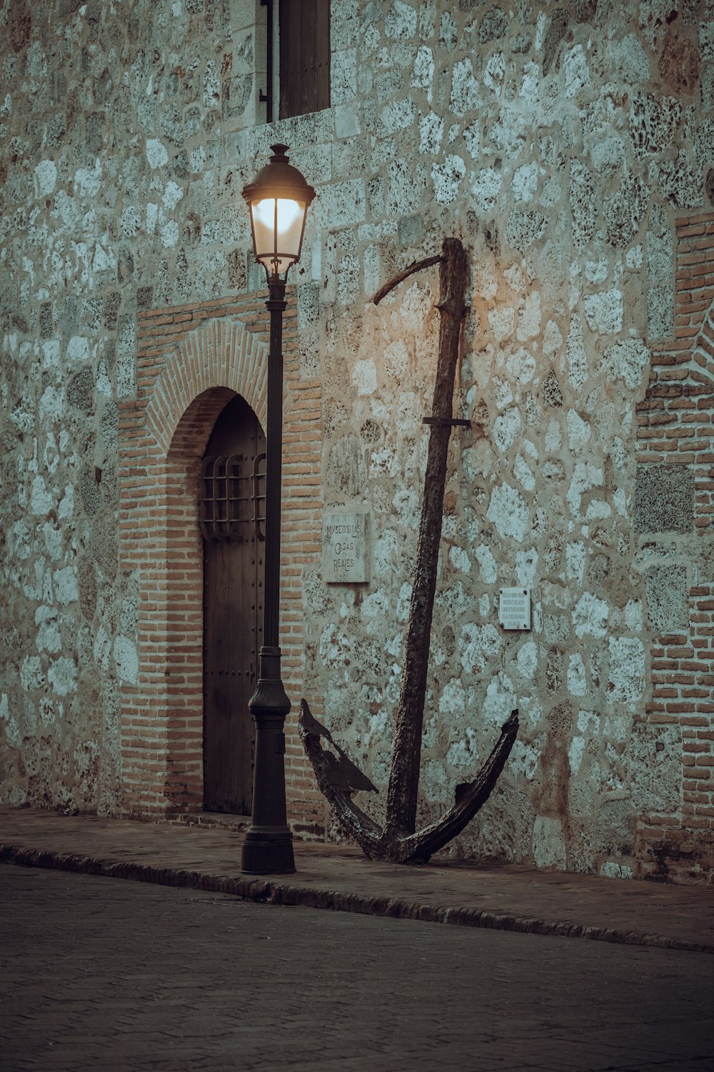 an old fashioned street lamp next to a stone building