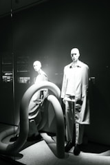 Mannequins dressed in minimalist tailored outfits in a modern showroom.