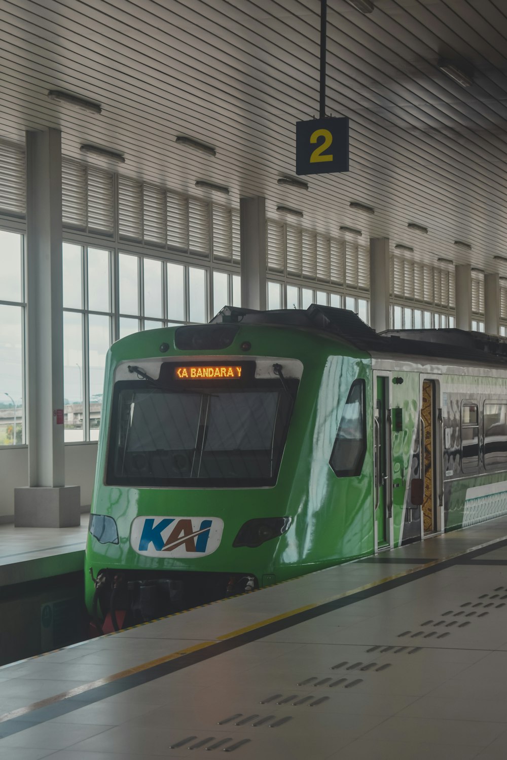 a green train pulling into a train station