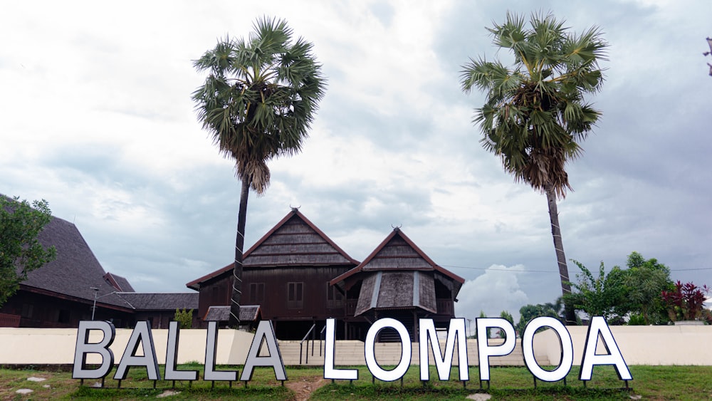 a sign that says balla lompoa in front of some palm trees