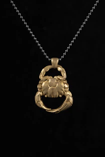 a gold crab pendant on a black background
