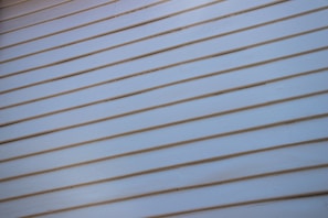 A close-up view of a light-colored wooden wall with horizontal siding, where each plank is neatly aligned and evenly spaced.