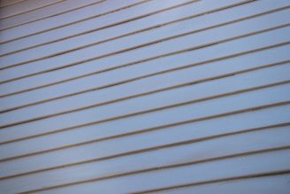 A close-up view of a light-colored wooden wall with horizontal siding, where each plank is neatly aligned and evenly spaced.