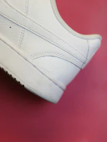 Close-up of trendy sneakers with pink and olive details on a white broken background.