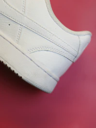 Close-up of a sleek beige leather heel resting on a crisp white surface with soft shadows.