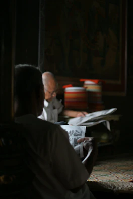 Partners sharing a quiet moment reading books side by side in a sunlit living room.