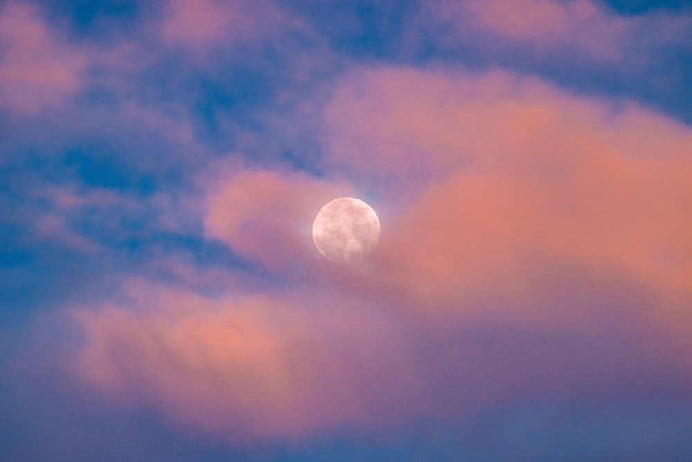 a full moon is seen through the clouds